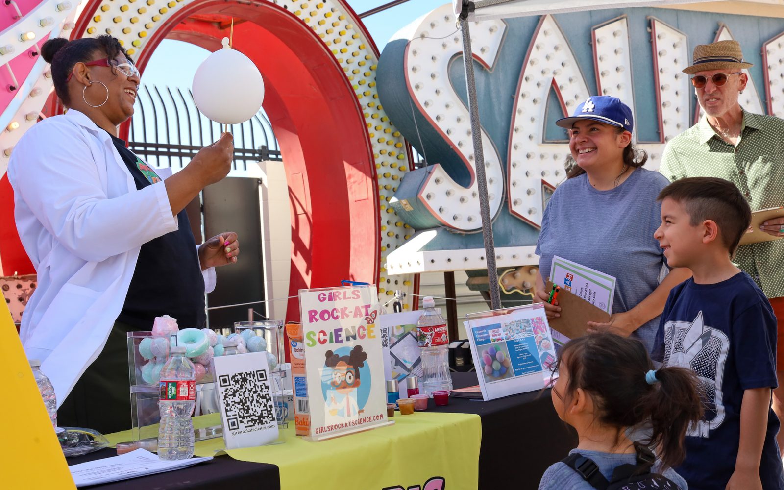 Children and family members around a booth in the Neon Boneyard.