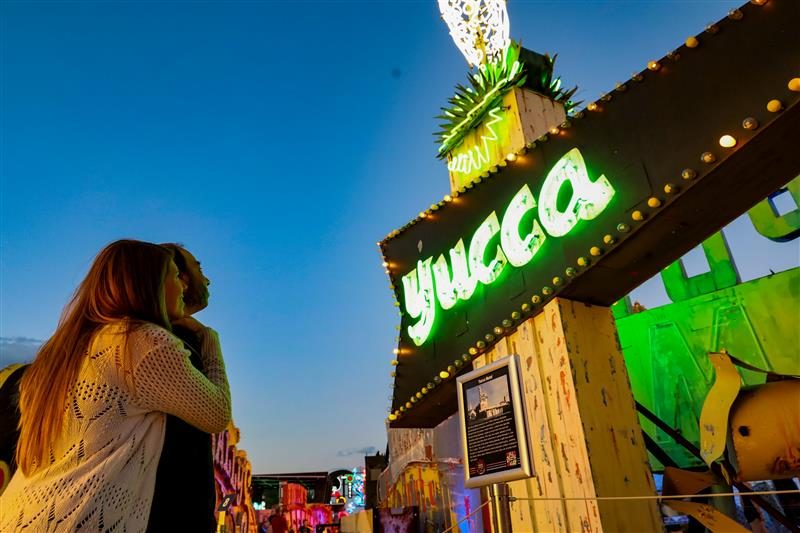 A couple holding each other as they look at the Yucca sign.