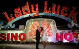A couple kissing in front of the Lady Luck sign.