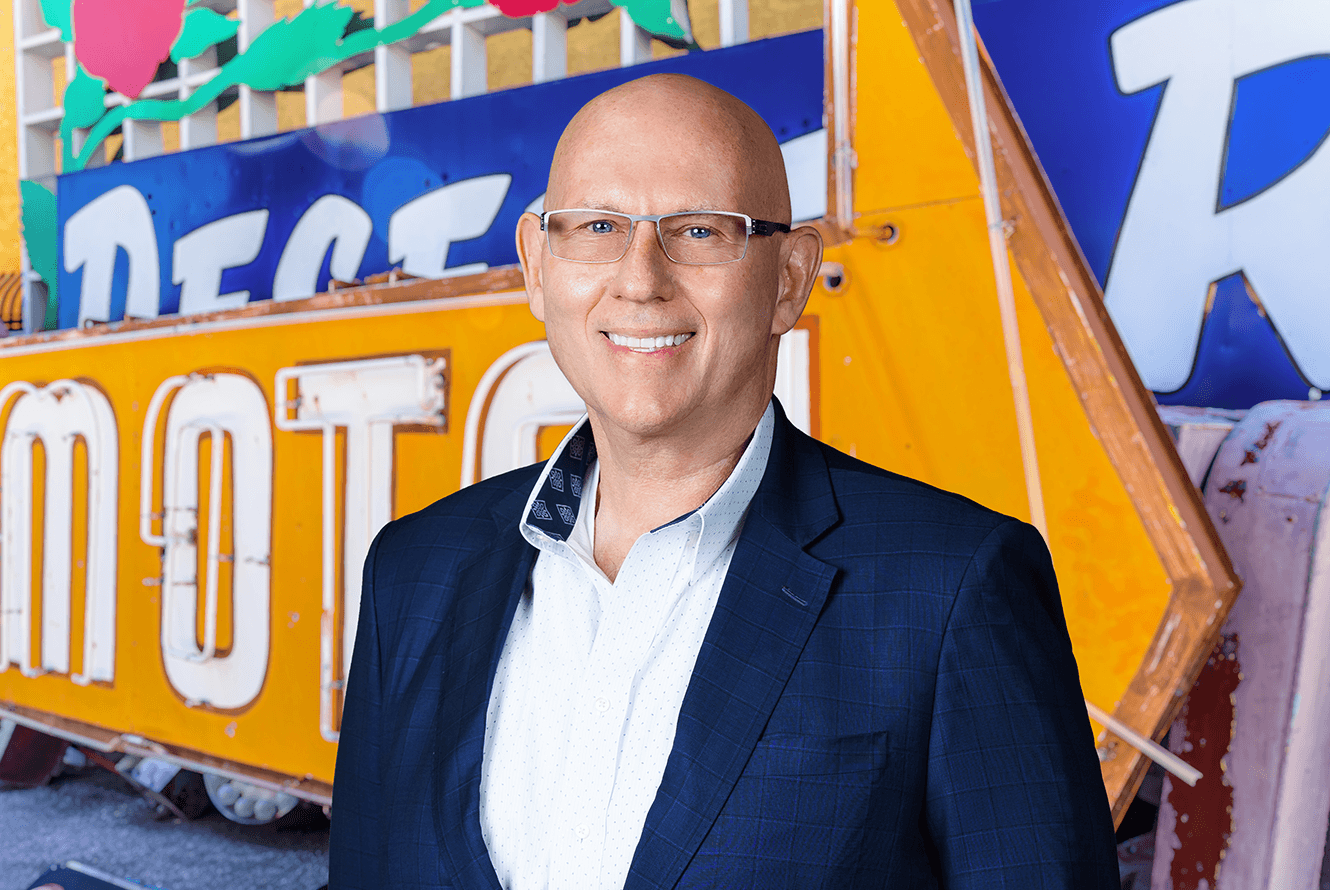 Image of Mike Dini in front of neon signs at the Neon Museum. Mike is the Chief Marketing Officer