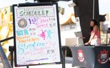 An image of the performance schedule of STEAM Family Fest with a DJ in the background.
