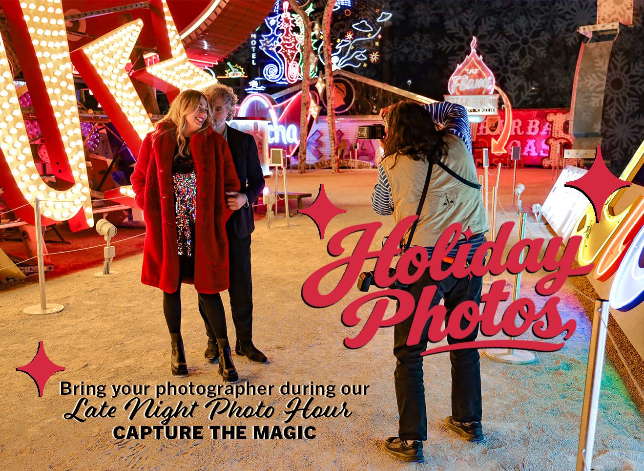 Image of a man and a woman, man in a dark suit and woman in a red cashmere jacket in front of the Stardust sign taking holiday photos at The Neon Museum